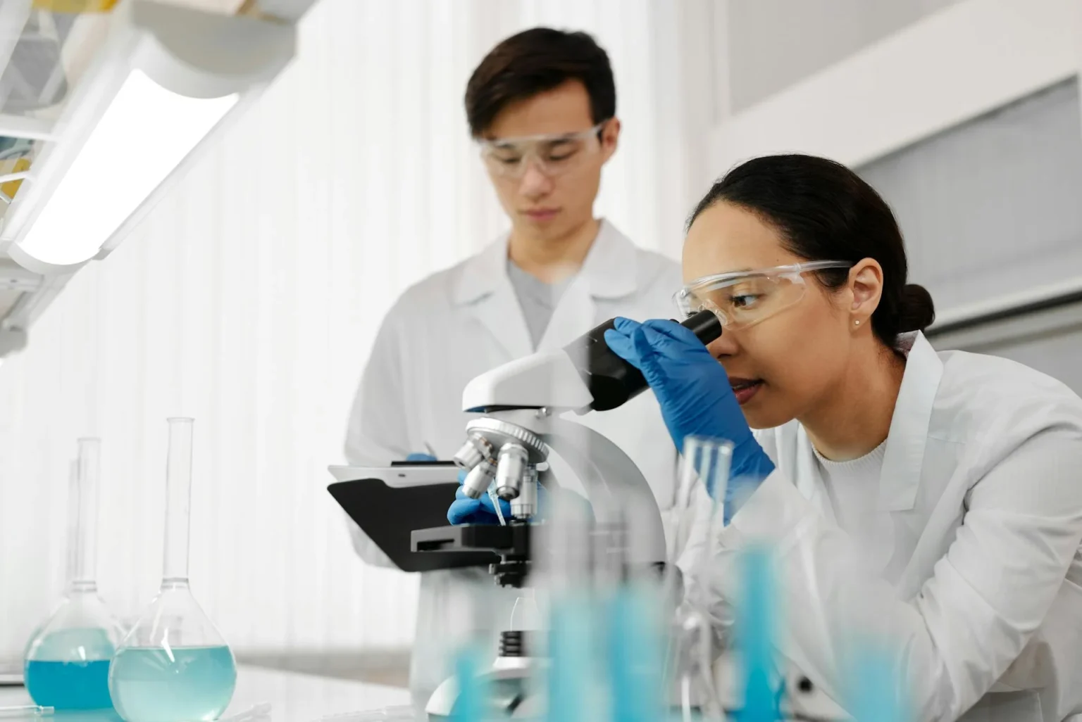 Two scientists use microscope